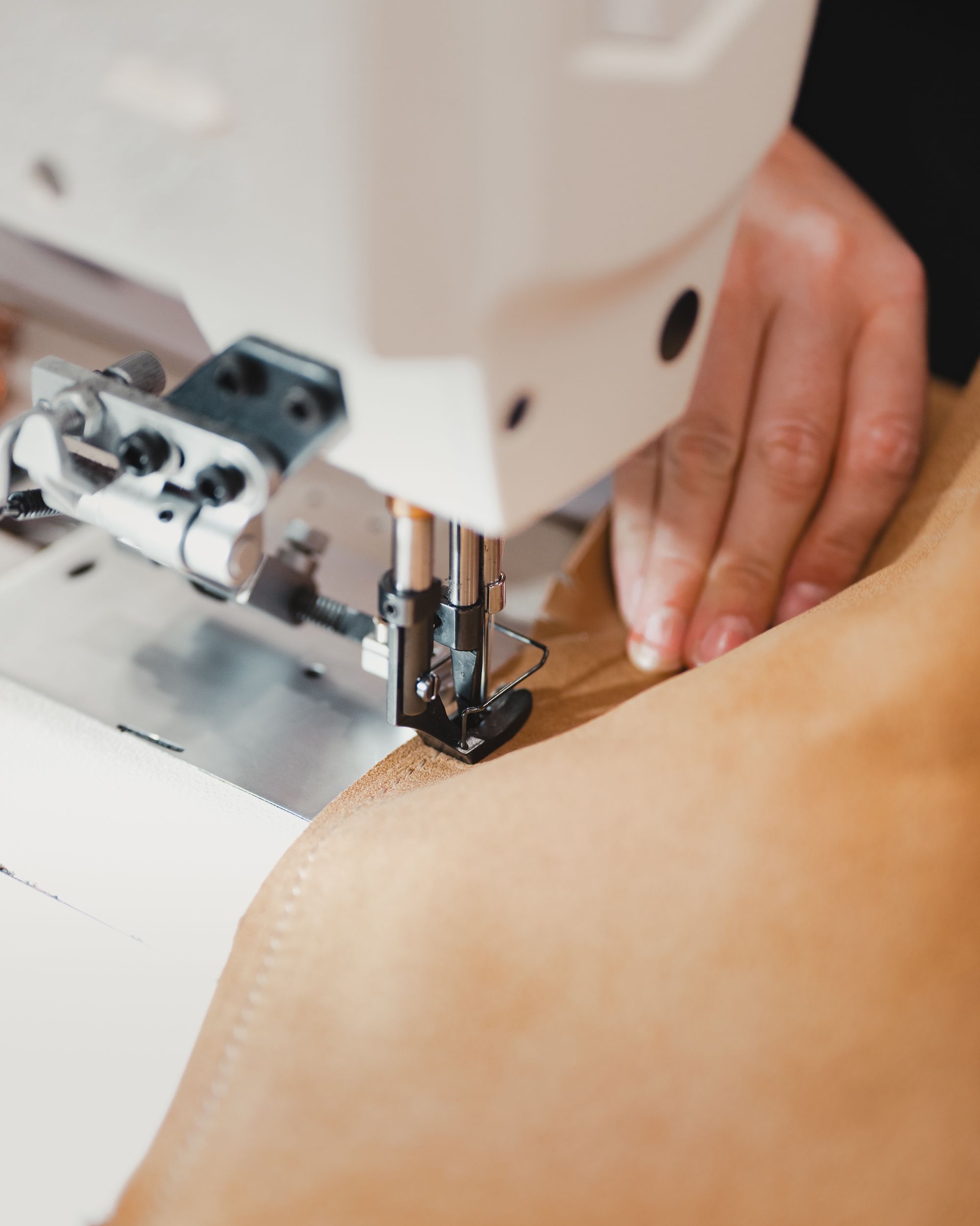 An automotive trimmer stitching natural leather at an industrial sewing machine
